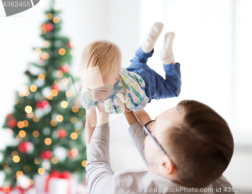 Image of happy father playing with son at christmas