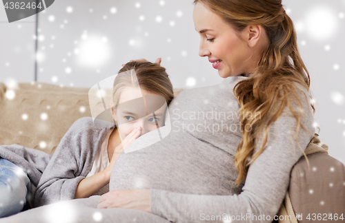 Image of pregnant woman and girl talking to baby in belly