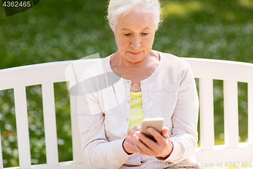 Image of senior woman with smartphone at summer park