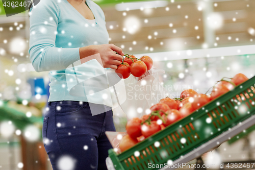 Image of customer with bag buying tomatoes at grocery store