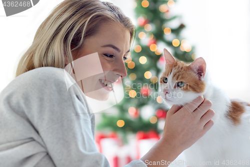 Image of happy young woman with cat at christmas
