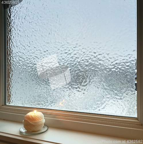 Image of Candle burning near frosted window