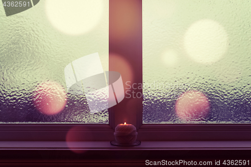 Image of Winter window with burning candle and bokeh lights