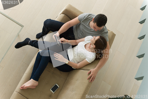 Image of couple relaxing at  home with tablet computers