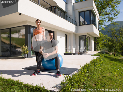 Image of woman and personal trainer doing exercise with pilates ball