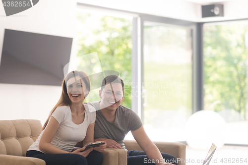 Image of couple relaxing at  home with tablet and laptop computers