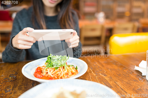 Image of Woman taking photo on her dish and posting on social network 