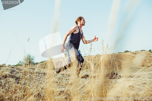 Image of Running sport. Man runner sprinting outdoor in scenic nature. Fit muscular male athlete training trail running for marathon run.