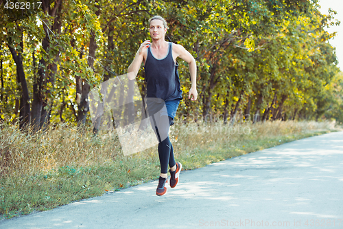 Image of Running sport. Man runner sprinting outdoor in scenic nature. Fit muscular male athlete training trail running for marathon run.