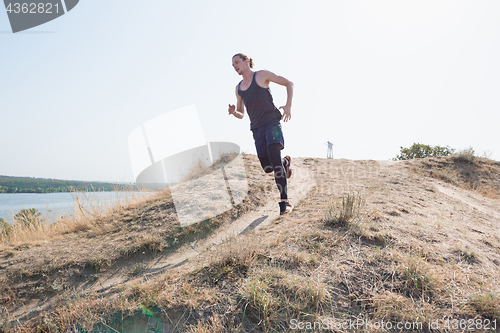 Image of Running sport. Man runner sprinting outdoor in scenic nature. Fit muscular male athlete training trail running for marathon run.