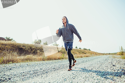 Image of Running sport. Man runner sprinting outdoor in scenic nature. Fit muscular male athlete training trail running for marathon run.