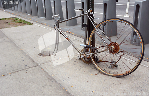 Image of Broken, rusty bicycle locked to a metal pole