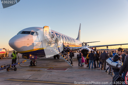 Image of People boarding on Ryanair Jet commercial airplane on Valencia airport at sunset.