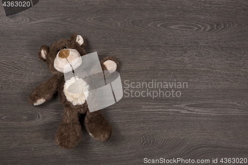 Image of Brown teddy bear on wooden background, top view