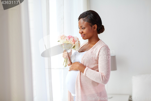 Image of happy african american pregnant woman with flowers