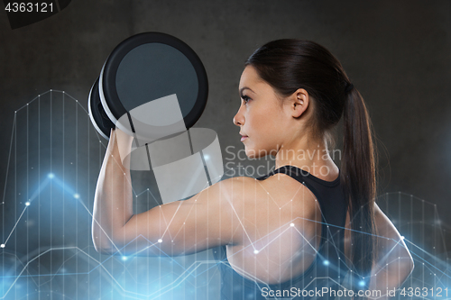 Image of young woman flexing muscles with dumbbells in gym