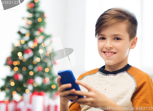 Image of close up of happy boy with smartphone at christmas