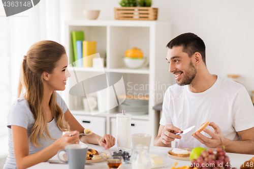 Image of happy couple having breakfast at home