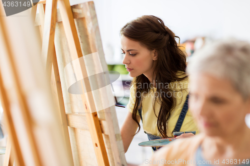 Image of student girl with easel painting at art school