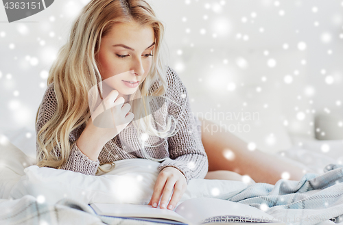 Image of young woman reading book in bed at home