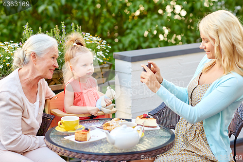 Image of woman photographing her family at cafe