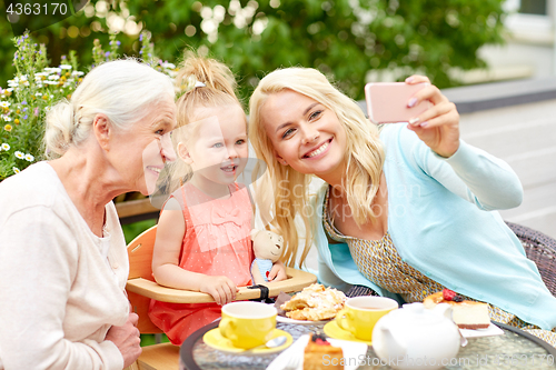 Image of happy family taking selfie at cafe