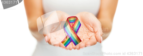 Image of female hands holding gay pride awareness ribbon