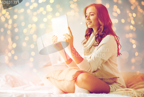 Image of happy young woman with tablet pc in bed at home