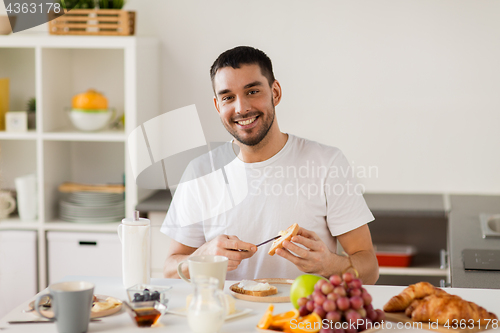 Image of man eating toast with coffee at home kitchen