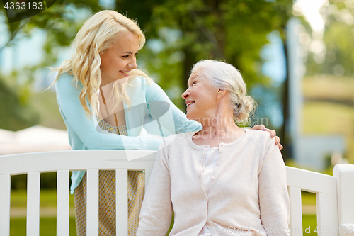 Image of daughter with senior mother hugging on park bench