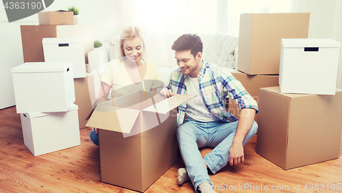 Image of smiling couple with big boxes moving to new home