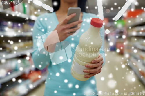 Image of customer with smartphone and milk at supermarket