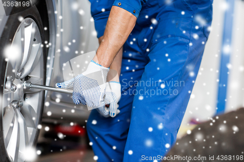 Image of auto mechanic with screwdriver changing car tire