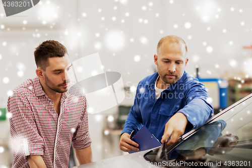 Image of auto mechanic with clipboard and man at car shop