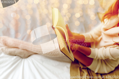 Image of close up of young woman reading book in bed