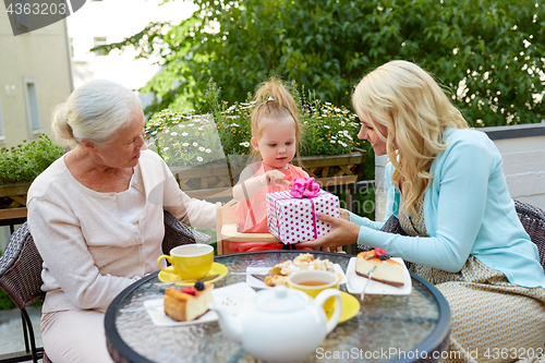 Image of happy mother giving present to little daughter at cafe