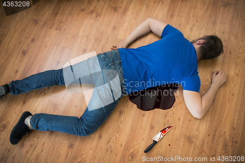 Image of dead man body lying on floor at crime scene