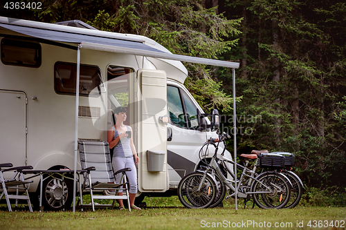 Image of Woman is standing with a mug of coffee near the camper RV.