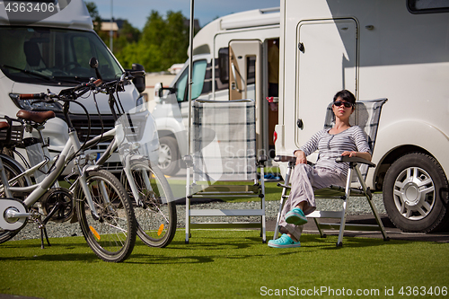 Image of Woman resting near motorhomes in nature. Family vacation travel,