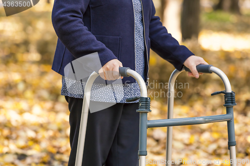 Image of Senior woman legs walking with walker in autumn park