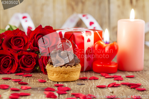 Image of Cupcake with cherry in front of bouquet of red roses and cadles