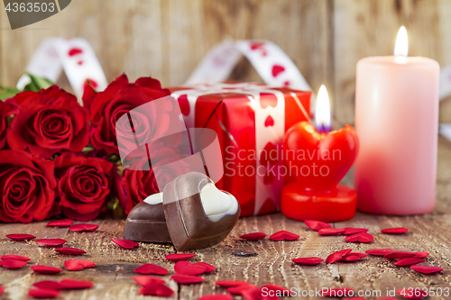 Image of Chocolate pralines in front of bouquet of red roses