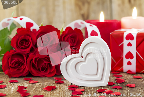 Image of Shape of white heart in front of bouquet of red roses