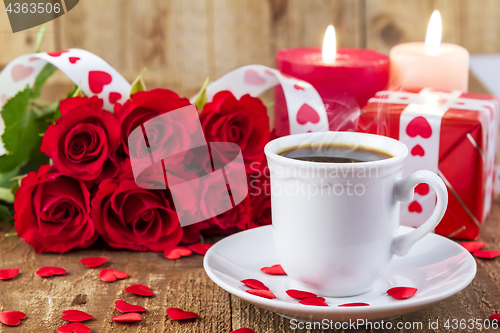 Image of Cup with coffee in front of bouquet of red roses