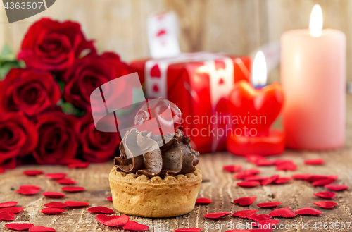 Image of Cupcake with cherry in front of bouquet of red roses