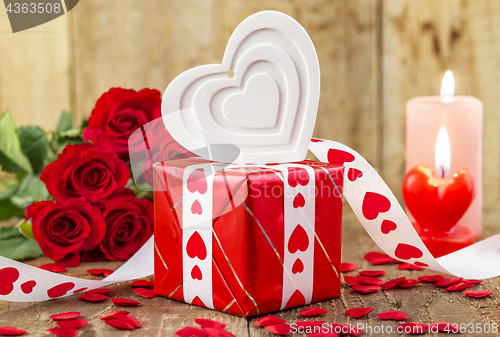 Image of Shape of white heart in front of bouquet of red roses