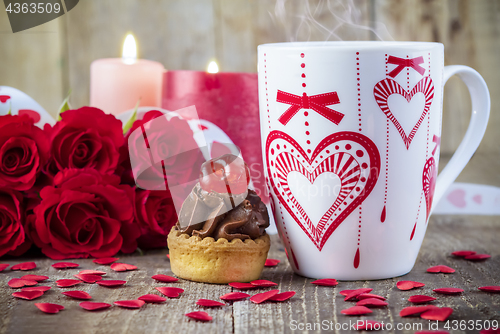 Image of Cupcake with cherry in front of bouquet of red roses