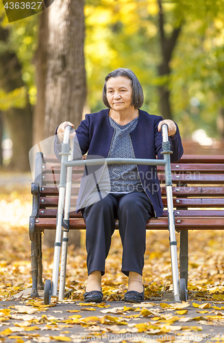 Image of Senior woman with walker getting up and walking outdoors