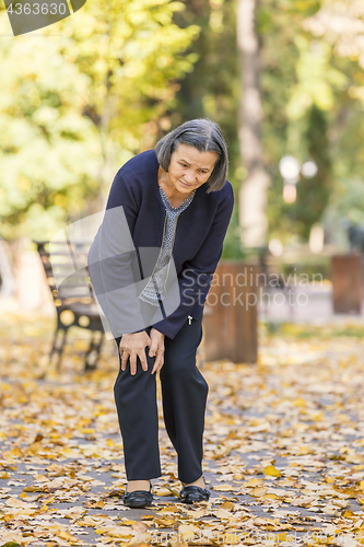 Image of Senior woman having knee pain walking in park