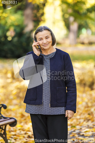 Image of Senior woman talking on smartphone outdoors